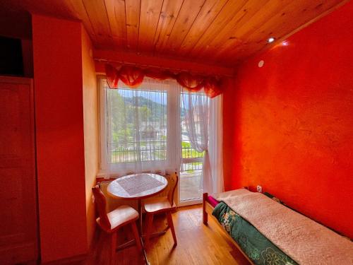 a bedroom with red walls and a table and a window at Turbacz pokoje gościnne in Ochotnica Górna