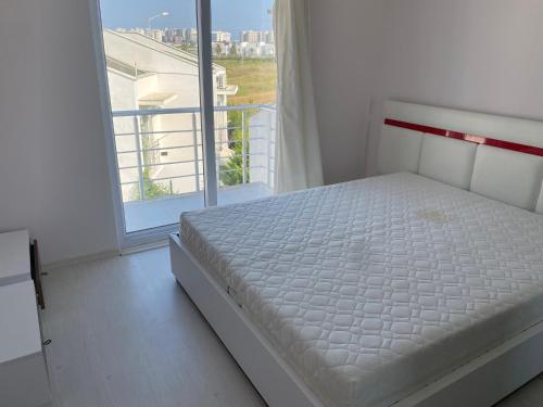 a white bed in a room with a window at Denize 800 m uzaklıkta villamız in Aksu
