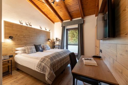 a bedroom with a bed and a desk and a television at Hotel Derby in Folgarida