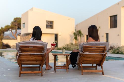 two women sitting in lawn chairs by a pool at Itida Suites in Sitia