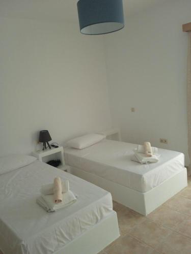 Dos camas en una habitación blanca con toallas. en Iliachtida apartments, en Filótion