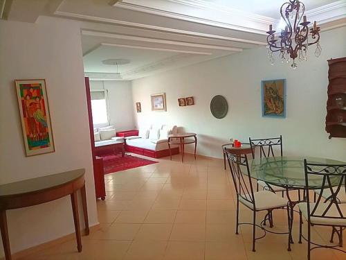 - un salon avec une table et des chaises en verre dans l'établissement appartement de vacances, à Kenitra