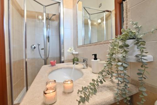 a bathroom with a sink with candles and a shower at IzzHome Flamingo in Pula