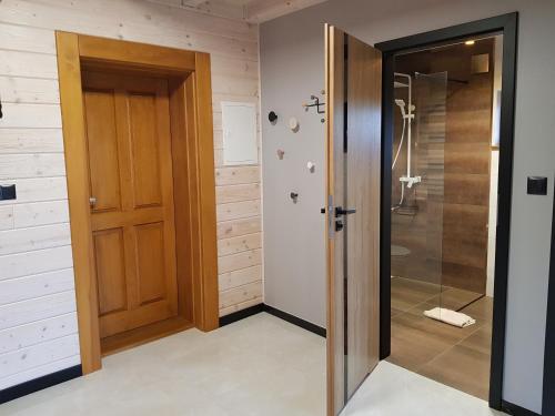 een badkamer met een douche en een houten deur bij Dom nad Biebrzą - Siedlisko Wroceń 57 in Wroceń