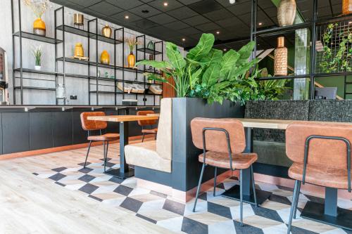a restaurant with chairs and a counter with plants at Distrikt Hotels Amsterdam Zaandam in Zaandam