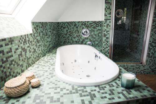 ein Badezimmer mit einer weißen Badewanne und einem grünen Fliesenboden in der Unterkunft Appartement du Mont de L’Enclus in Buisestraat