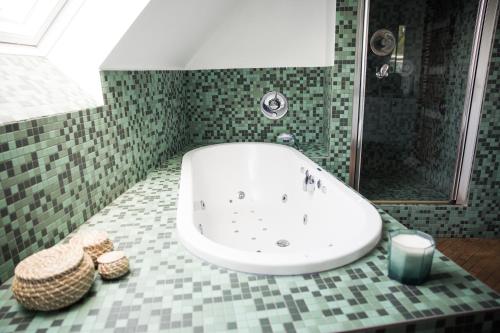 a bathroom with a white tub and a green tiled floor at Appartement du Mont de L’Enclus in Buisestraat