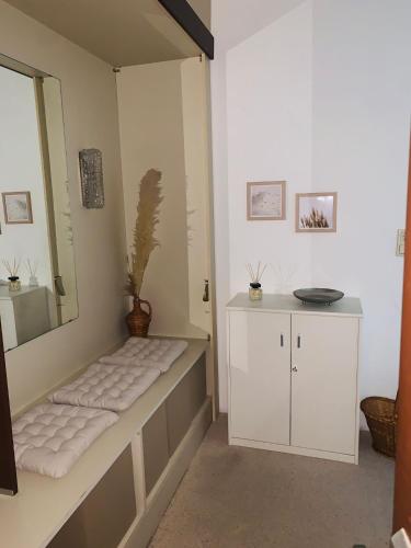 a bathroom with a white bench and a mirror at Ferienwohnung Paula in Bad Harzburg