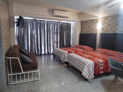 sypialnia z 2 łóżkami, krzesłem i oknem w obiekcie Suite Claus w Acapulco