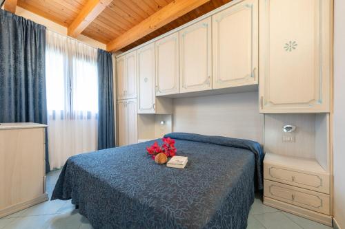 Un dormitorio con una cama con flores y un libro en Palm Village en Villasimius