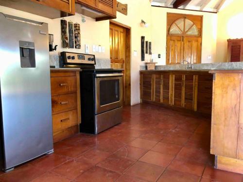a kitchen with a stainless steel refrigerator and cabinets at Parrot Estate Villa in Englishmanʼs Bay