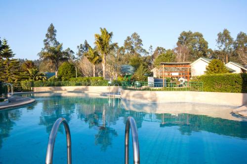 - une piscine d'eau bleue en face d'une maison dans l'établissement Hotel y Cabañas Huallilemu Sur - Caja Los Andes, à El Quisco
