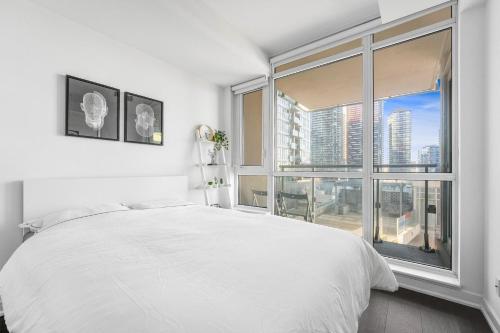 een slaapkamer met een wit bed en een groot raam bij Heart of Downtown Toronto! in Toronto