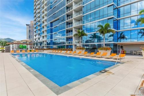 a large swimming pool with chairs and a building at Luxury Residence at Kakaako in Honolulu