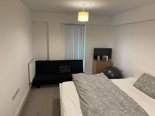 a bedroom with two beds and a black couch at Modern/Spacious Apartment in Digbeth (5 minute walk from Bullring) in Birmingham