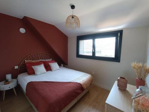 Schlafzimmer mit einem Bett mit roter und weißer Bettwäsche und einem Fenster in der Unterkunft Villa en bord de mer in Jullouville-les-Pins