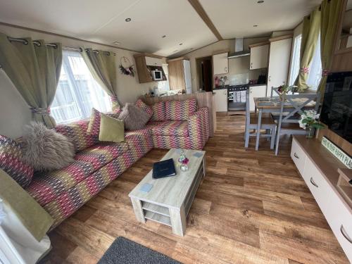 a living room with a couch and a table at Lakeside Retreat 1 with hot tub, private fishing peg situated at Tattershall Lakes Country Park in Tattershall