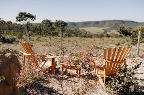 two chairs and a table in a field with flowers at Paradise Ranch Chapada dos Veadeiros in Alto Paraíso de Goiás