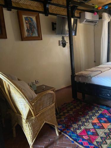 a bedroom with a bed and a chair and a table at Riad Azurite in Chefchaouene
