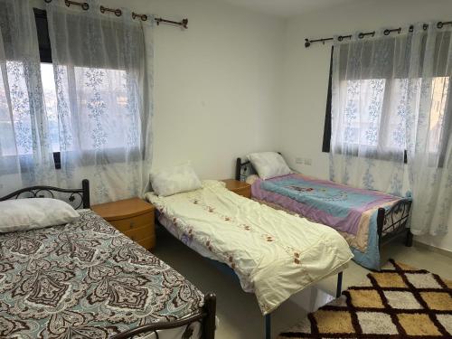 two beds in a room with windows and curtains at Ghanem building 15 in Bethlehem