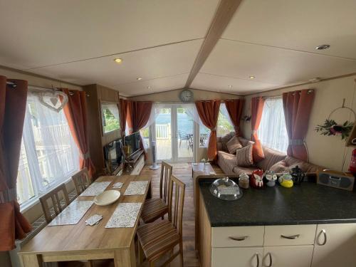 cocina y sala de estar con mesa y caravana en Lakeside Retreat 2 with hot tub, private fishing peg situated at Tattershall Lakes Country Park, en Tattershall