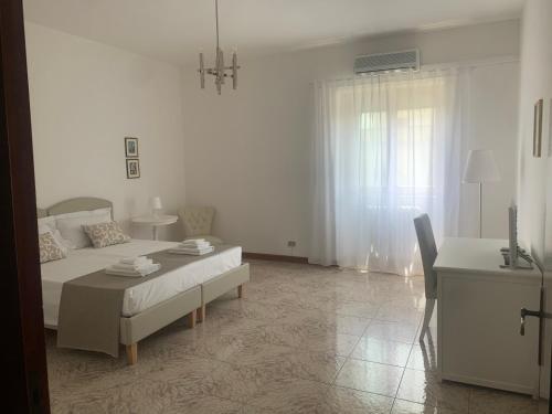 a white bedroom with a bed and a table at Porta Napoli Rooms in Lecce