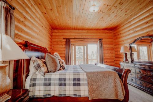 ein Schlafzimmer mit einem Bett in einer Holzhütte in der Unterkunft Fiddler Lake Resort Chalet 96 Elk in Mille-Isles