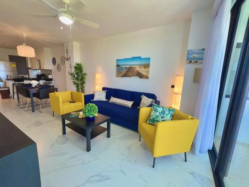 a living room with a blue couch and yellow chairs at Cana Rock Star, Apartamento Lujo Vista Golf Infinity Pool A-410 in Punta Cana