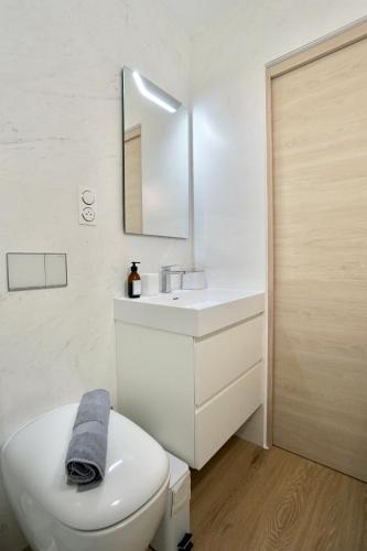 une salle de bain avec des toilettes blanches et un lavabo dans l'établissement Rose des sables * front de mer*, à Ploemeur