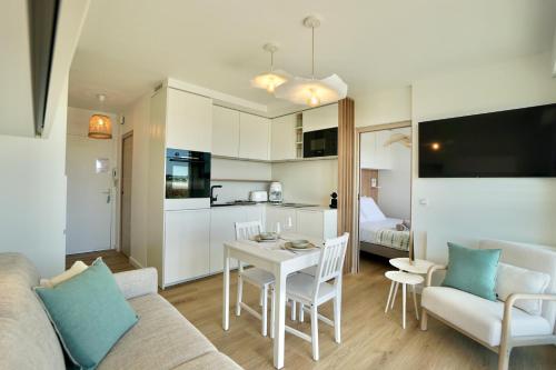 ein Wohnzimmer mit einem Sofa und einem Tisch sowie eine Küche in der Unterkunft Rose des sables * front de mer* in Ploemeur
