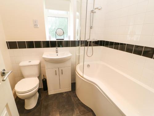 a bathroom with a toilet and a tub and a sink at 195 Durham Road in Consett