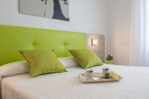 Hotel Solemare - Frontemare - 3 Stelle Superior في ليدو دي يسولو: سرير مع اللوح الأمامي الأخضر وصينية مع الزهور عليها