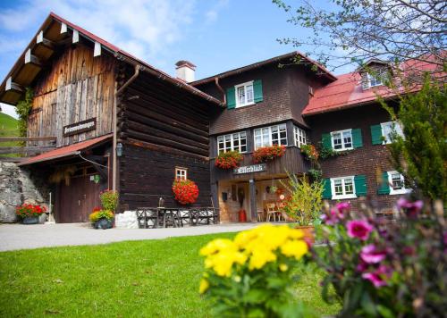 una gran casa de madera con flores delante en Alpenpension Elferblick, en Hirschegg