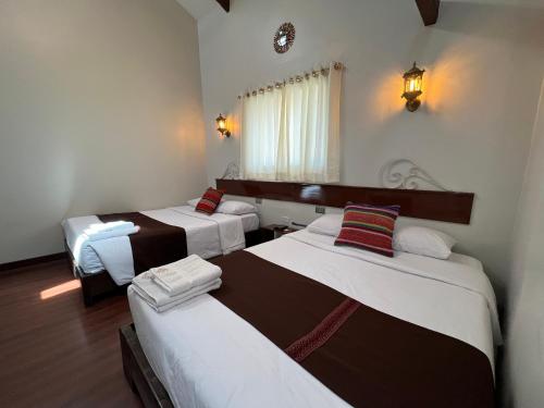une chambre avec trois lits dans une pièce dans l'établissement Hotel Andina, à Cusco