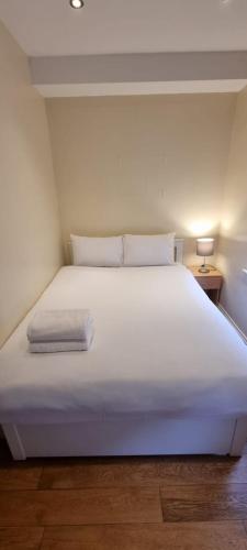 un grande letto bianco in una stanza con una lampada di Sootheus - Soho71 a Londra