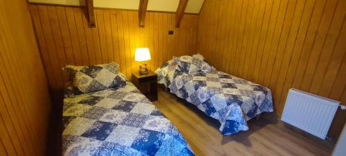 2 Betten in einem Zimmer mit einer Lampe auf einem Tisch in der Unterkunft Cabañas Nevados Del Valle in Malalcahuello