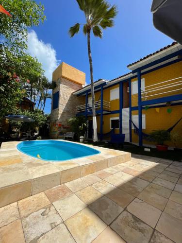 a swimming pool in front of a house with a palm tree at Pousada Girassol in Porto De Galinhas