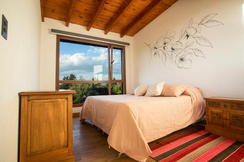 sypialnia z łóżkiem i dużym oknem w obiekcie Studio Los Manzanos w mieście Bariloche