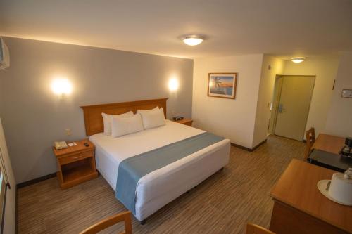 a hotel room with a large bed and a table at Araiza Palmira Hotel y Centro de Convenciones in La Paz