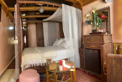 sypialnia z łóżkiem z baldachimem i stołem w obiekcie Riad Azurite w mieście Szafszawan