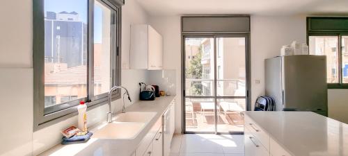a kitchen with white counters and a large window at BnBIsrael Apartments - Hakovshim Marguerite in Tel Aviv