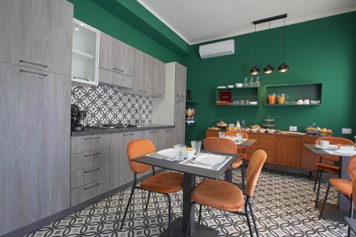 uma cozinha com paredes verdes e uma mesa e cadeiras em Malù - Bed & Breakfast em Agrigento