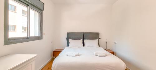 a bedroom with a white bed with two pillows at BnBIsrael Apartments - Hakovshim Marguerite in Tel Aviv