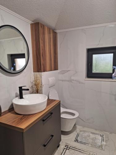 a bathroom with a sink and a toilet and a mirror at Apartment Hara, luxury lakeside suite with exquisite view in Jablanica