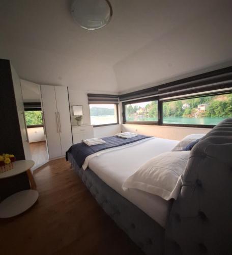 a bedroom with a large white bed with windows at Apartment Hara, luxury lakeside suite with exquisite view in Jablanica