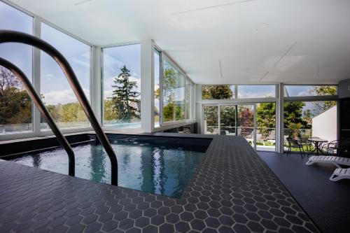 a swimming pool in a house with windows at Villa Bauhaus Labi Garden wellness apartman in Siófok