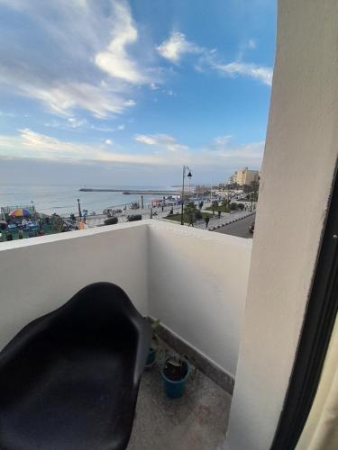 une chaise noire assise sur un balcon avec vue sur l'océan dans l'établissement Résidence artistique Vue sur mer, à Larache