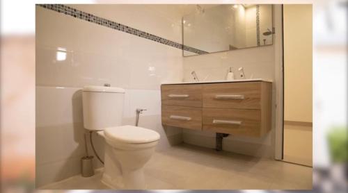 a white bathroom with a toilet and a sink at Maison sympathique ! Entièrement équipée in Bamako