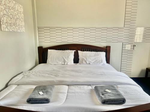 a white bed with two towels on top of it at J2 INN in Uttaradit