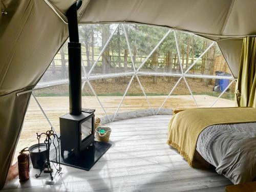 a bedroom with a stove in a tent at Cambridgeshire Glamping in Fowlmere